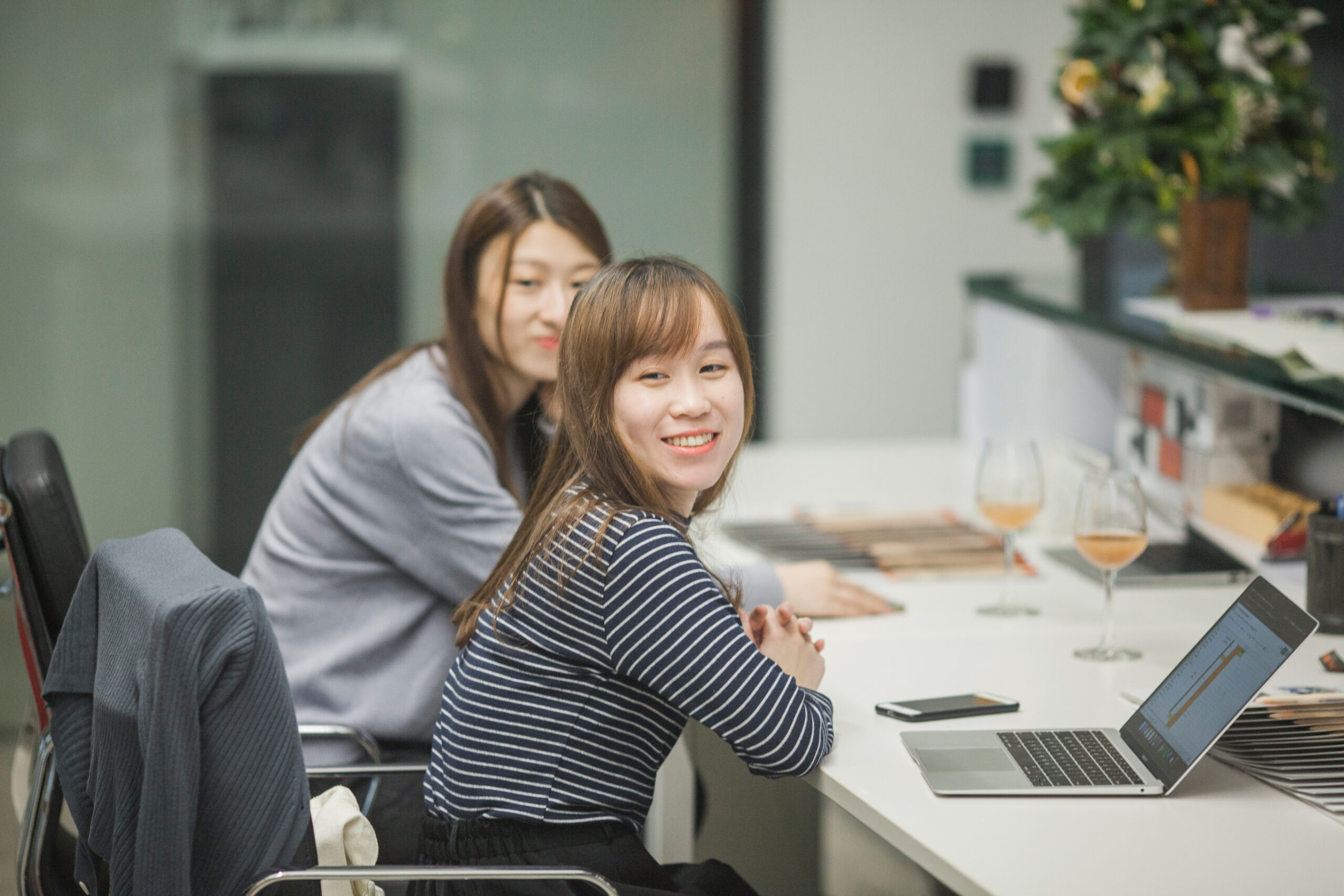 Two Asian women working at a coworking space with laptops.