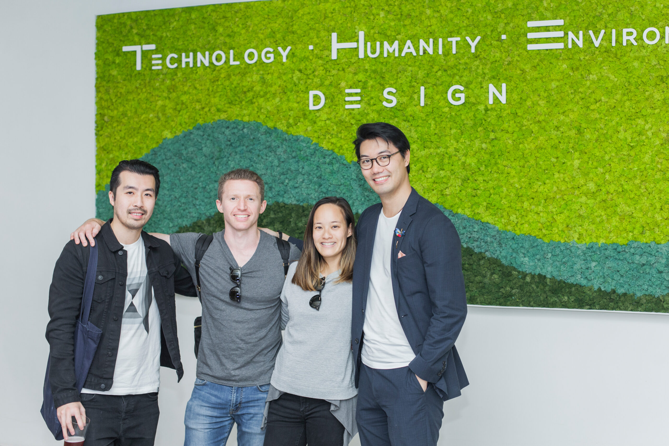 A group of people posing in front of a sign at a coworking space.